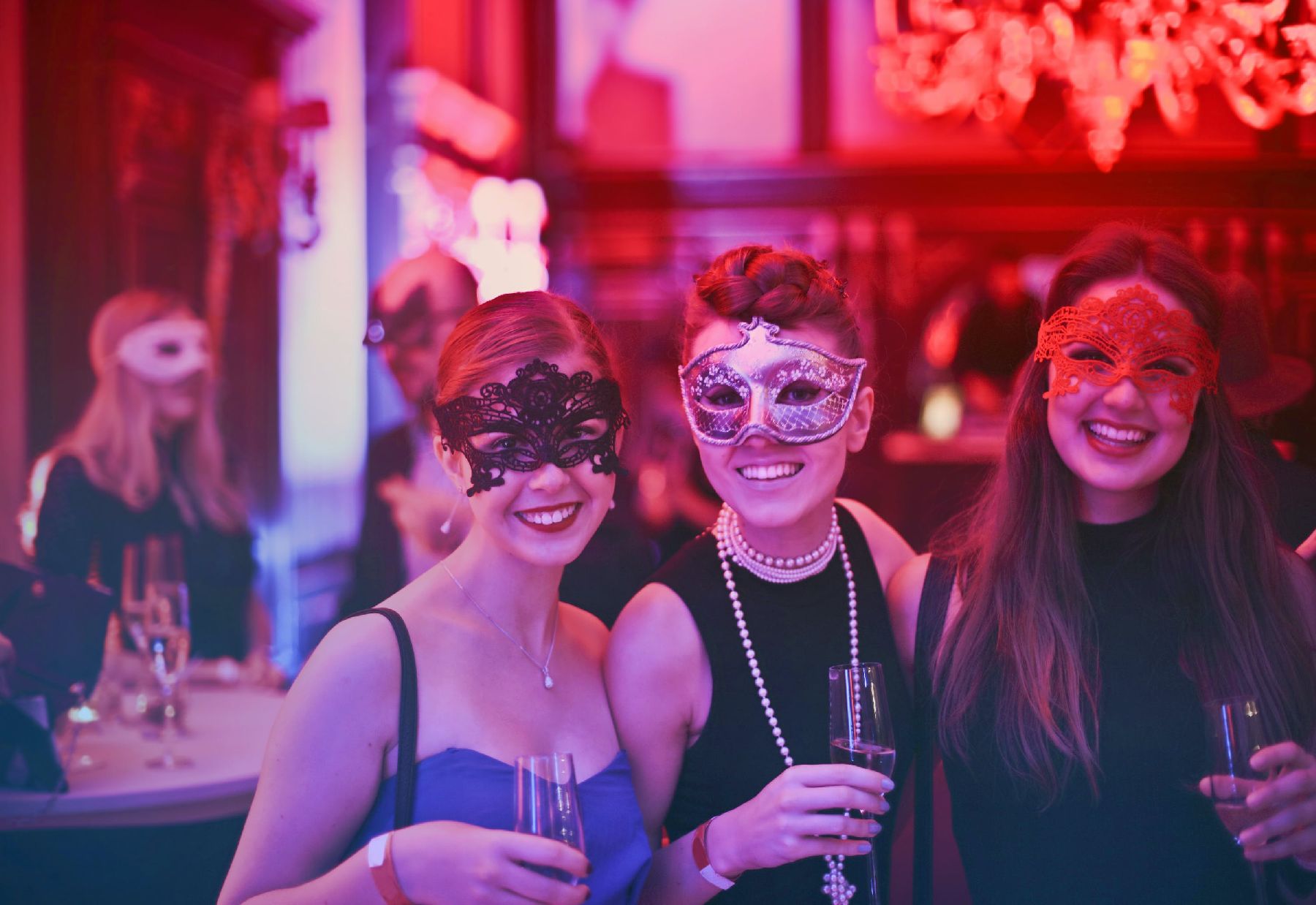3 women smiling at a party in masks